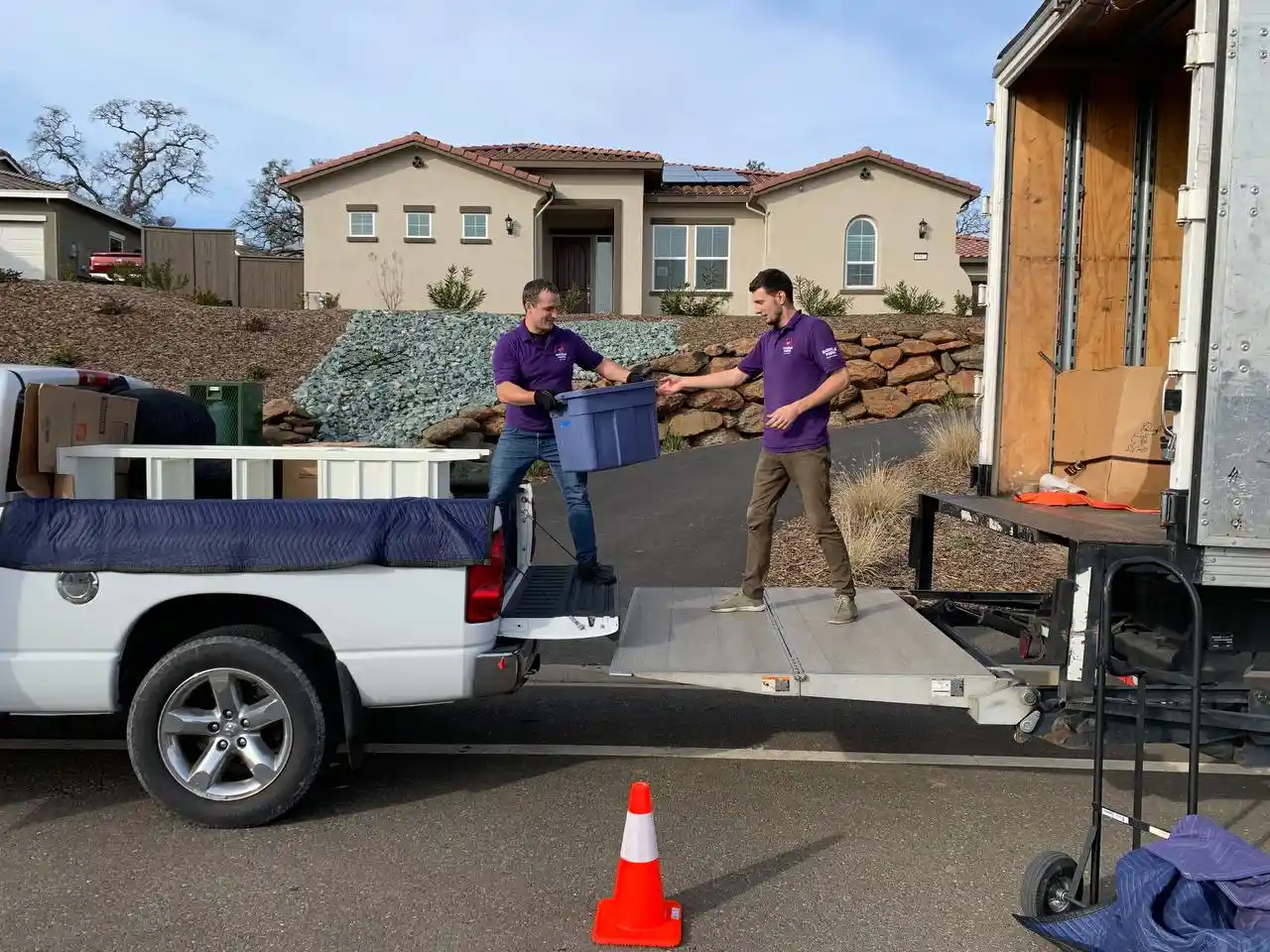Movers passing a reusable moving bin near the truck