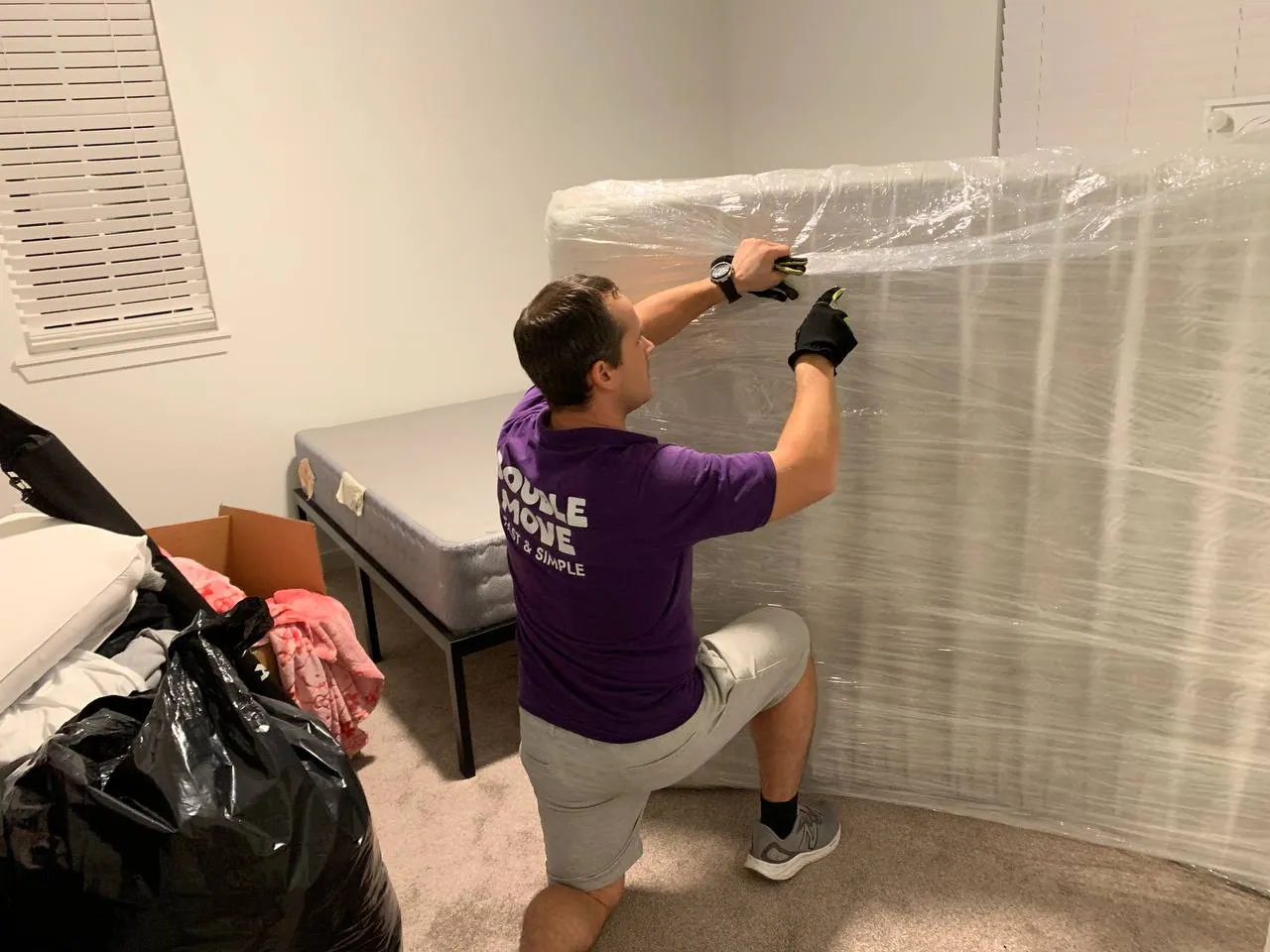 Mover carefully shrink-wrapping a mattress